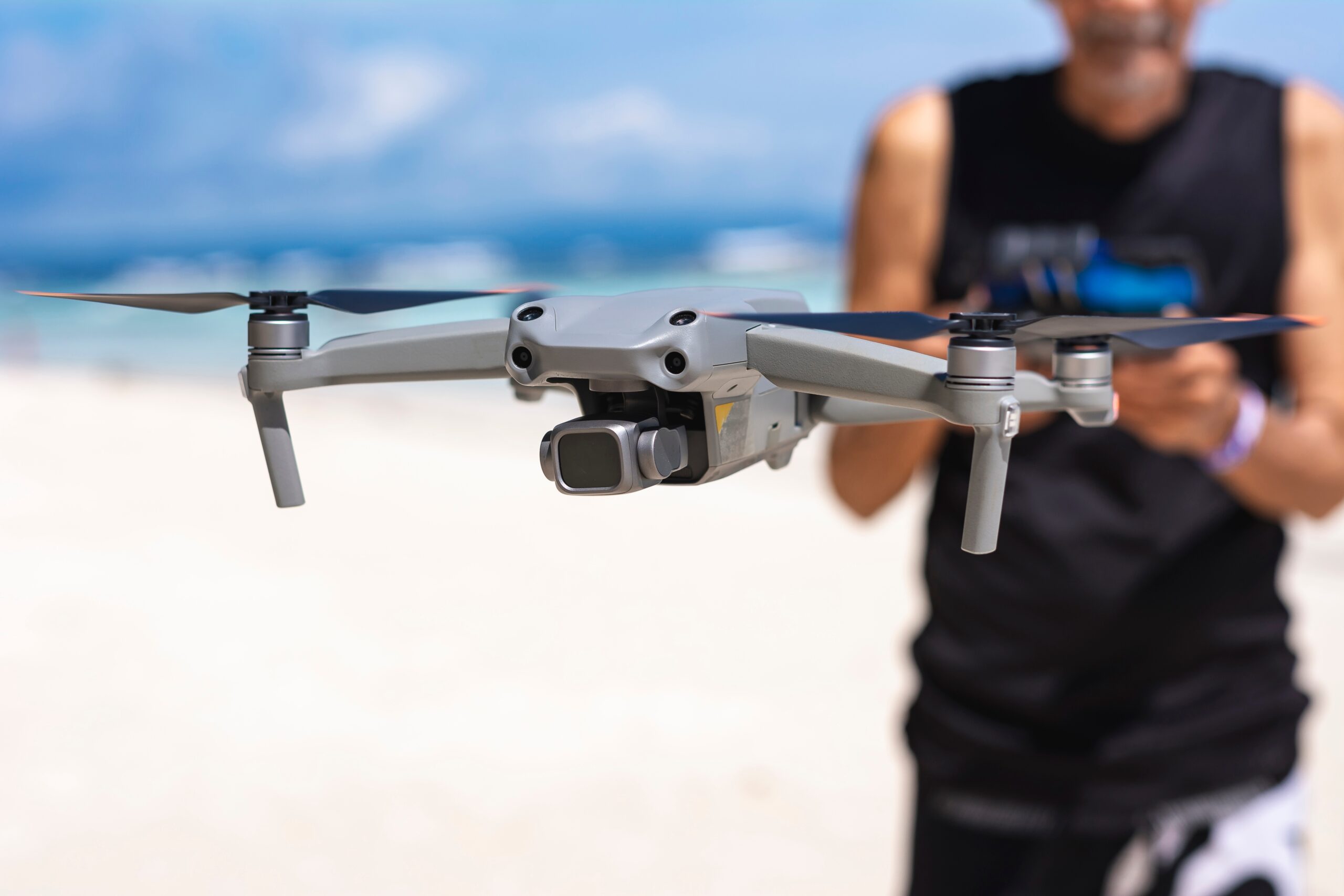An,Old,Man,Controlling,A,Small,Drone,At,The,Beach.